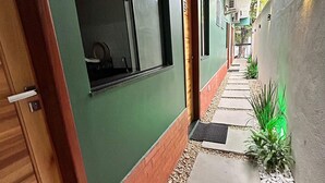 Un couloir étroit avec un mur vert, une porte en bois et une fenêtre.