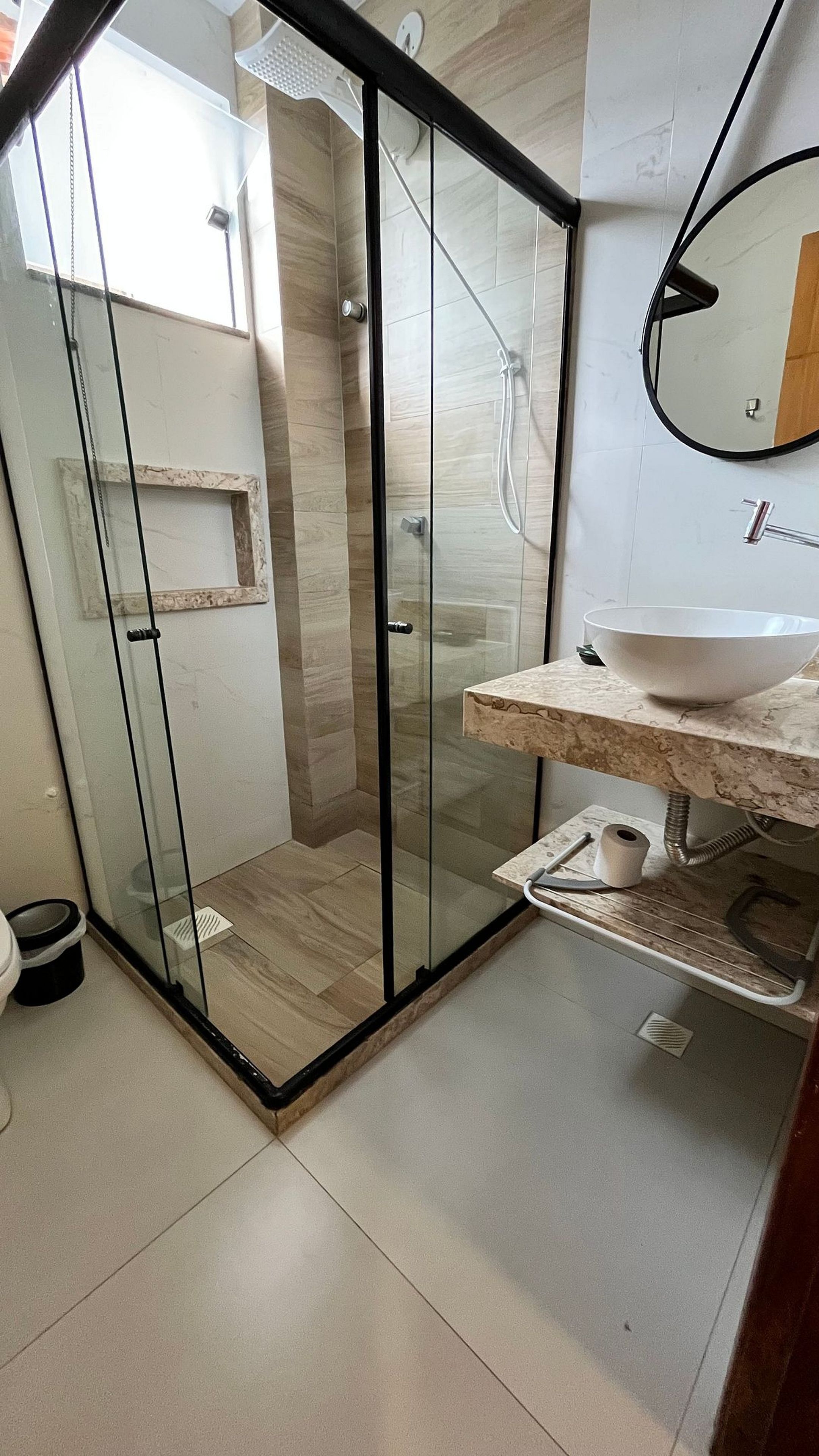 Ein modernes Badezimmer mit einer Duschkabine, einem Marmorwaschtisch und einer Toilette.