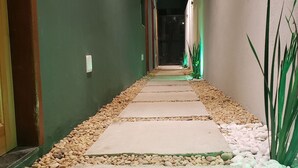 Ein Korridor mit einem Steinweg, grünen Wänden und einer Deckenleuchte.