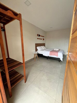 A bedroom with a wooden bunk bed, a single bed with a headboard, and a small round table. - Morada do Sol Suítes - Suíte 05 (Arraial do Cabo)
