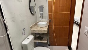 Ein kleines Badezimmer mit Toilette, Waschbecken und Spiegel.
