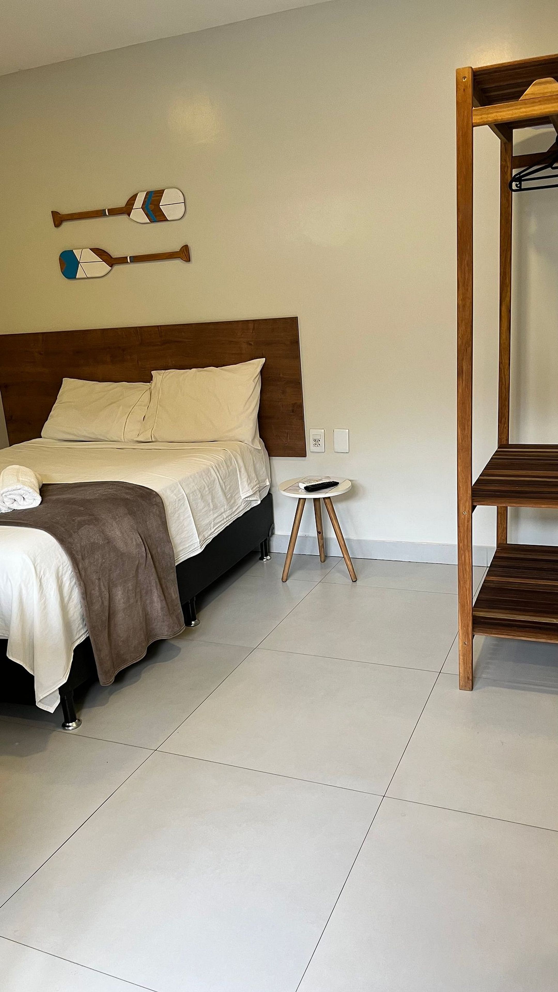 Quarto com cama, mesa de cabeceira e estante de madeira.