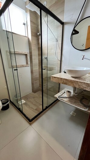 Un baño moderno con ducha de vidrio, lavamanos de mármol y un inodoro.