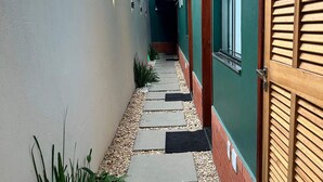 Un sentiero stretto con pietre a secco, fiancheggiato da un muro bianco e una porta in legno.