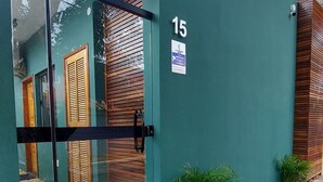 Un edificio moderno con ingresso tramite porta in vetro, numero 15, e un piccolo cartello che indica un'area di servizio attiva 24 ore su 24.