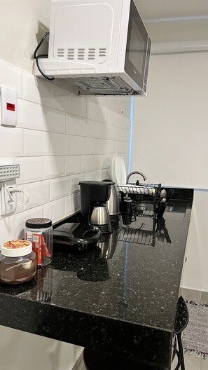 A kitchen with a microwave, coffee maker, and a dish rack.