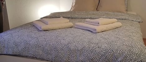 A neatly made bed with a patterned bedspread and two pillows.