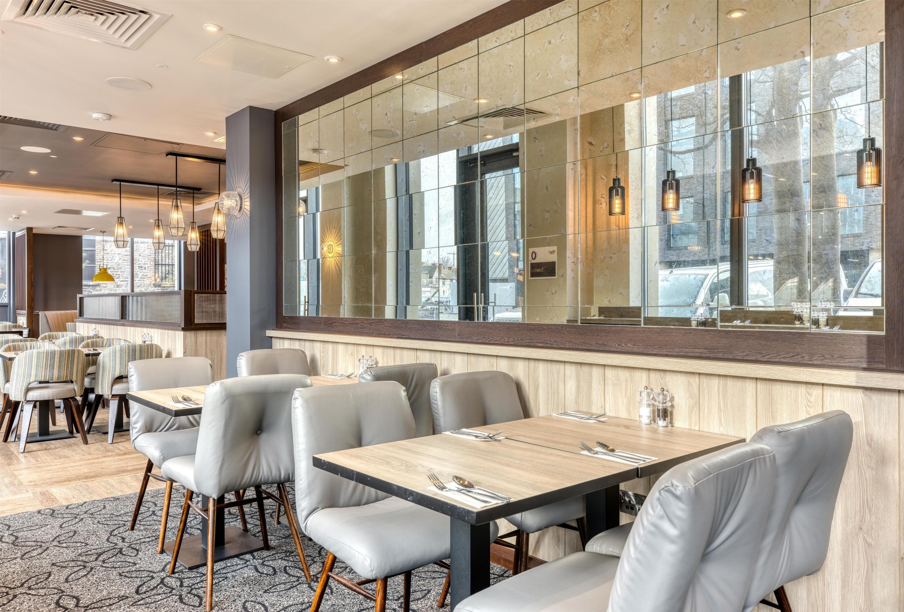 Un restaurante con un ventanal grande, mesas y sillas de madera.