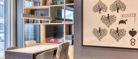 Una camera moderna con un tavolo da pranzo, sedie, una libreria e una parete decorata con un motivo a carte da gioco.