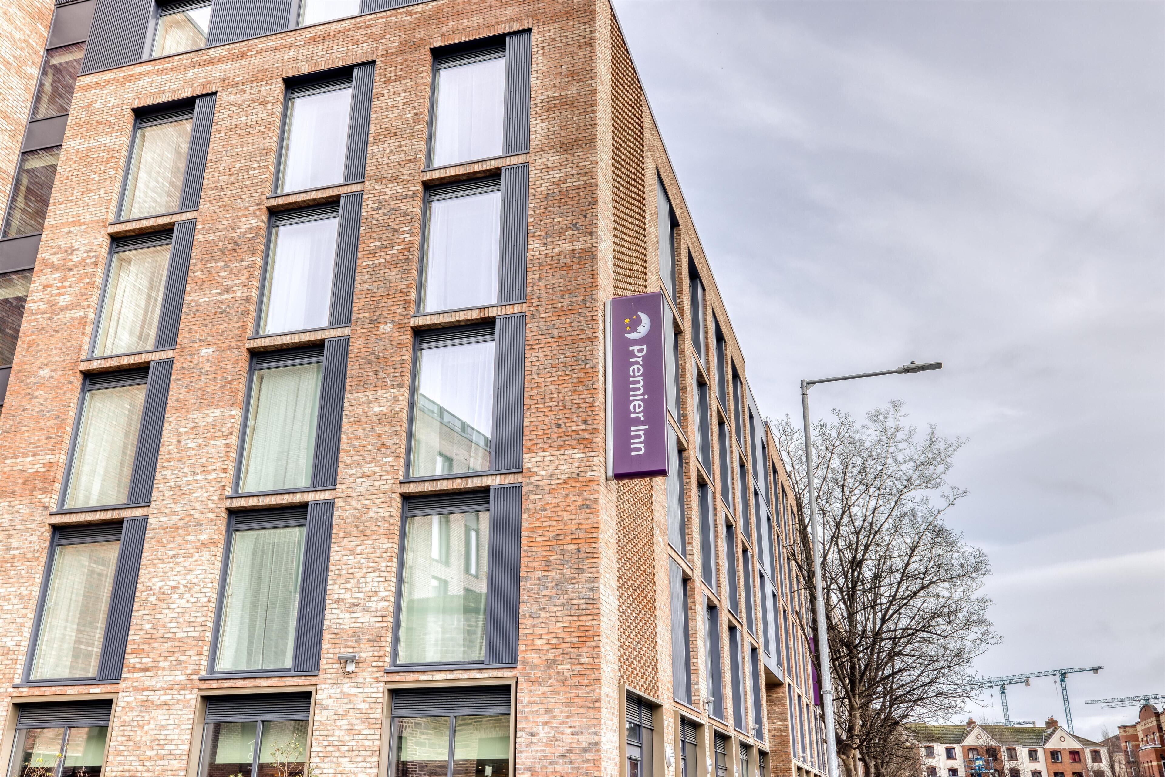 Un edificio de varios pisos con un llamativo letrero de 'Premier Inn', ventanas amplias y fachada de ladrillo.