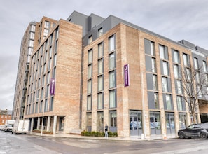 Un hotel de varios pisos con fachada de ladrillo, ventanas grandes y un llamativo letrero de Premier Inn.