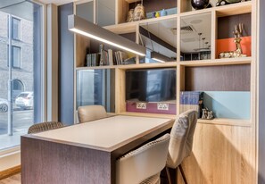 Un espacio de oficina moderno con un escritorio, sillas, estanterías y un ventanal grande.