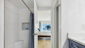 A hotel room with a bathroom, a bed, and a view of the sea. - 2BD/2BA Cocoa Beach Oceanfront + POOL & ALL of Downtown! (Cocoa Beach)