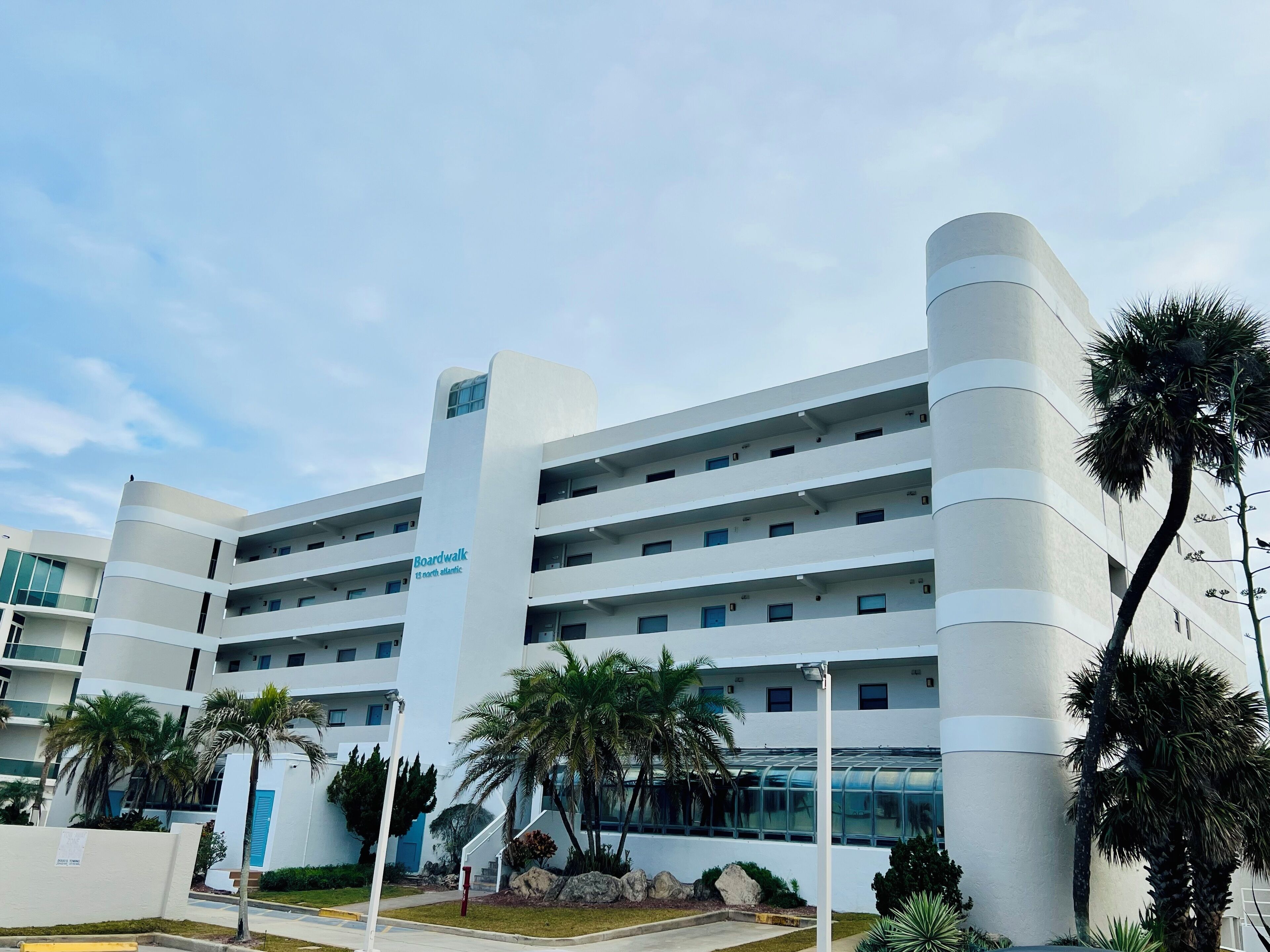 Un hotel de varios pisos con un diseño moderno, que cuenta con balcones en cada planta, una escalera central y un cartel que indica que es el número 13 North Atlantic.