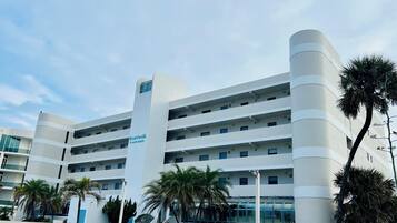 Un hotel de varios pisos con un diseño moderno, que cuenta con balcones en cada planta, una escalera central y un cartel que indica que es el número 13 North Atlantic.