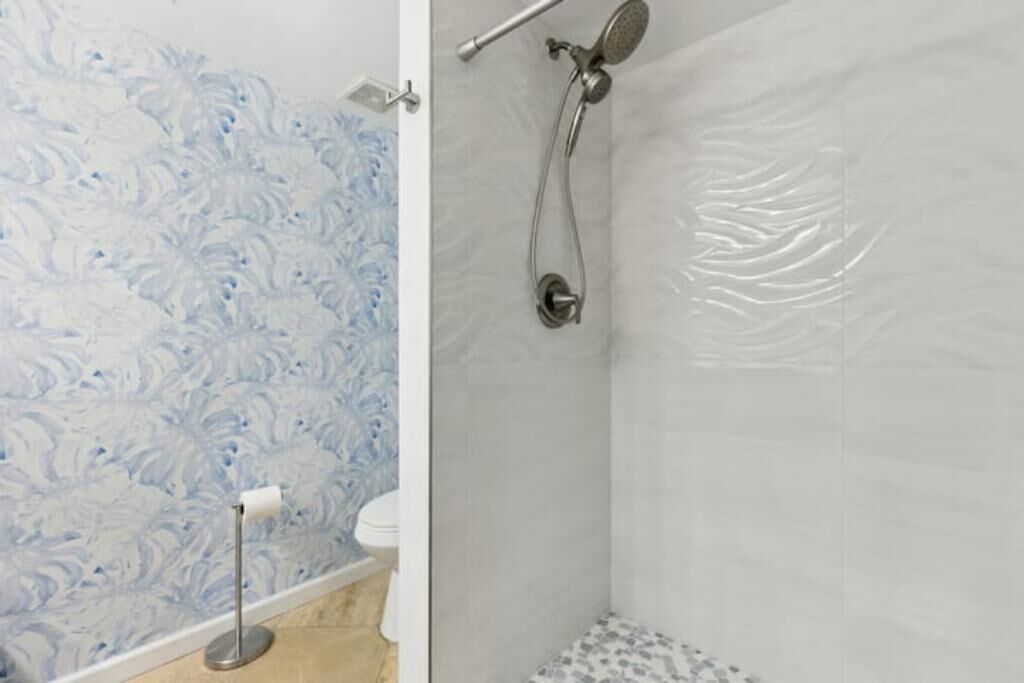 Un baño con pared de mármol, ducha y retrete.
