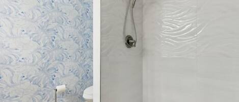 Un baño con pared de mármol, ducha y retrete.