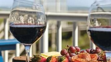 Una mesa con dos copas de vino y una bandeja de frutas en un balcón con vista a la ciudad.