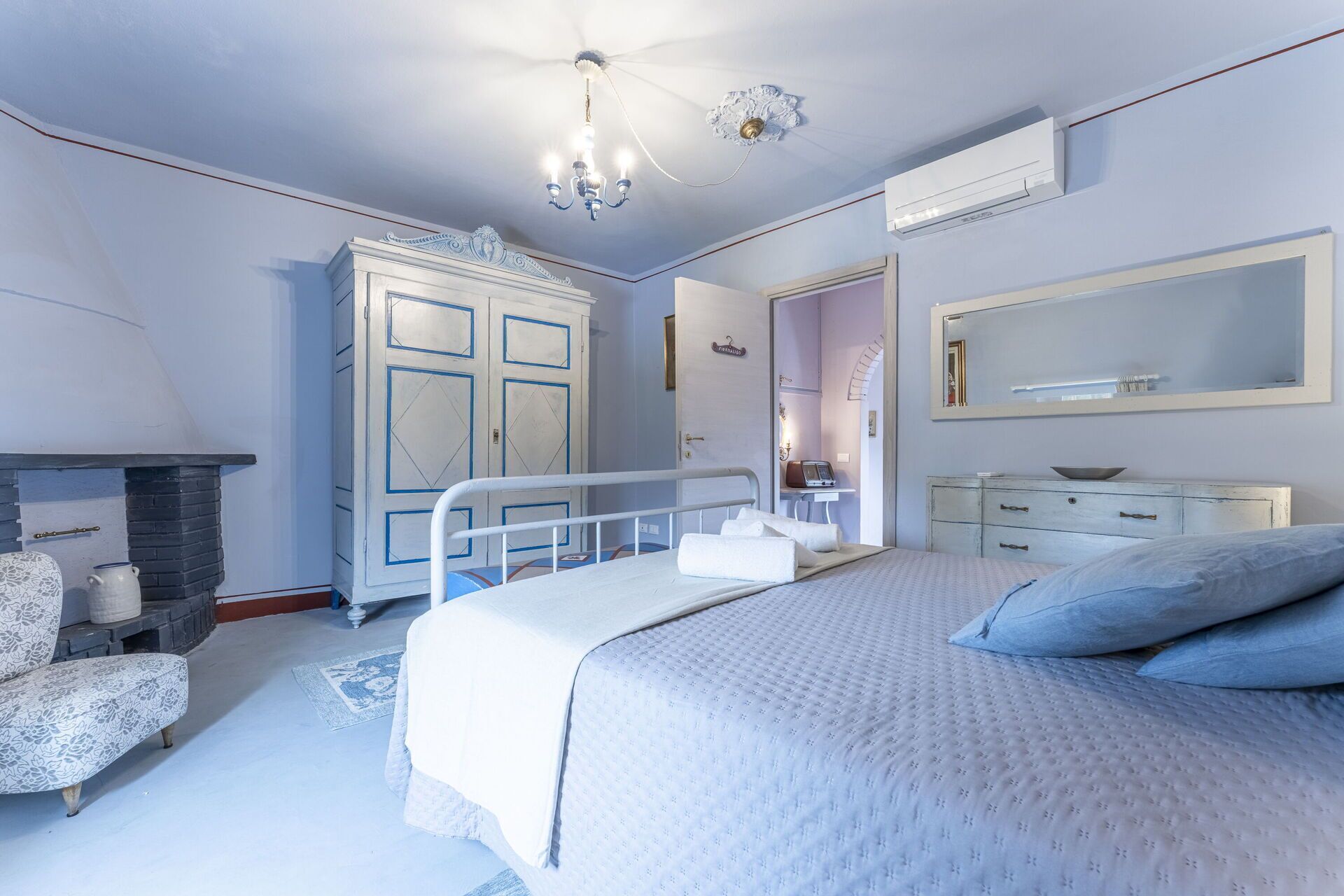 Un dormitorio con cama, cómoda, tocador y chimenea.