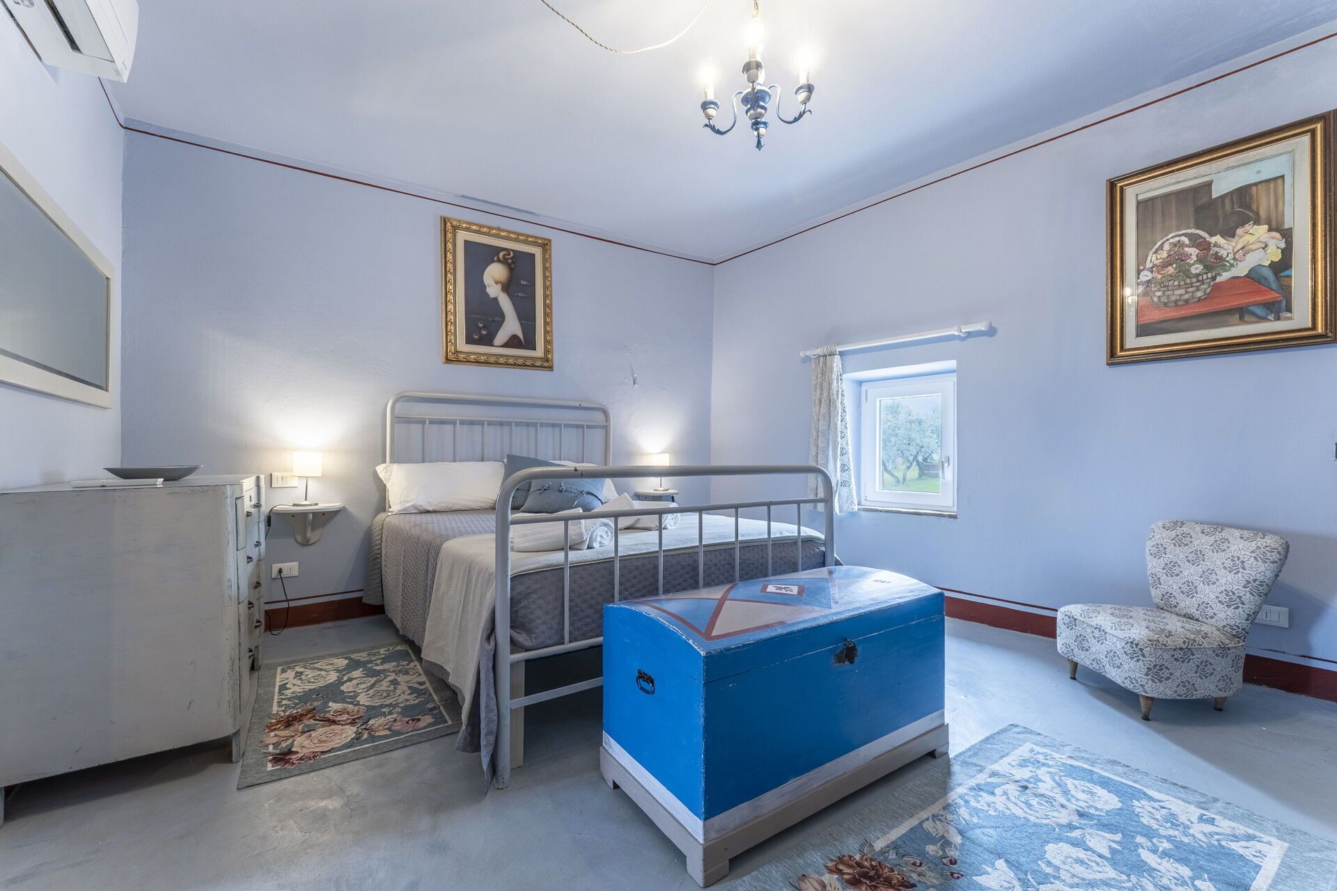 A bedroom with a bed, a dresser, a chair, a chest of drawers, and a window.