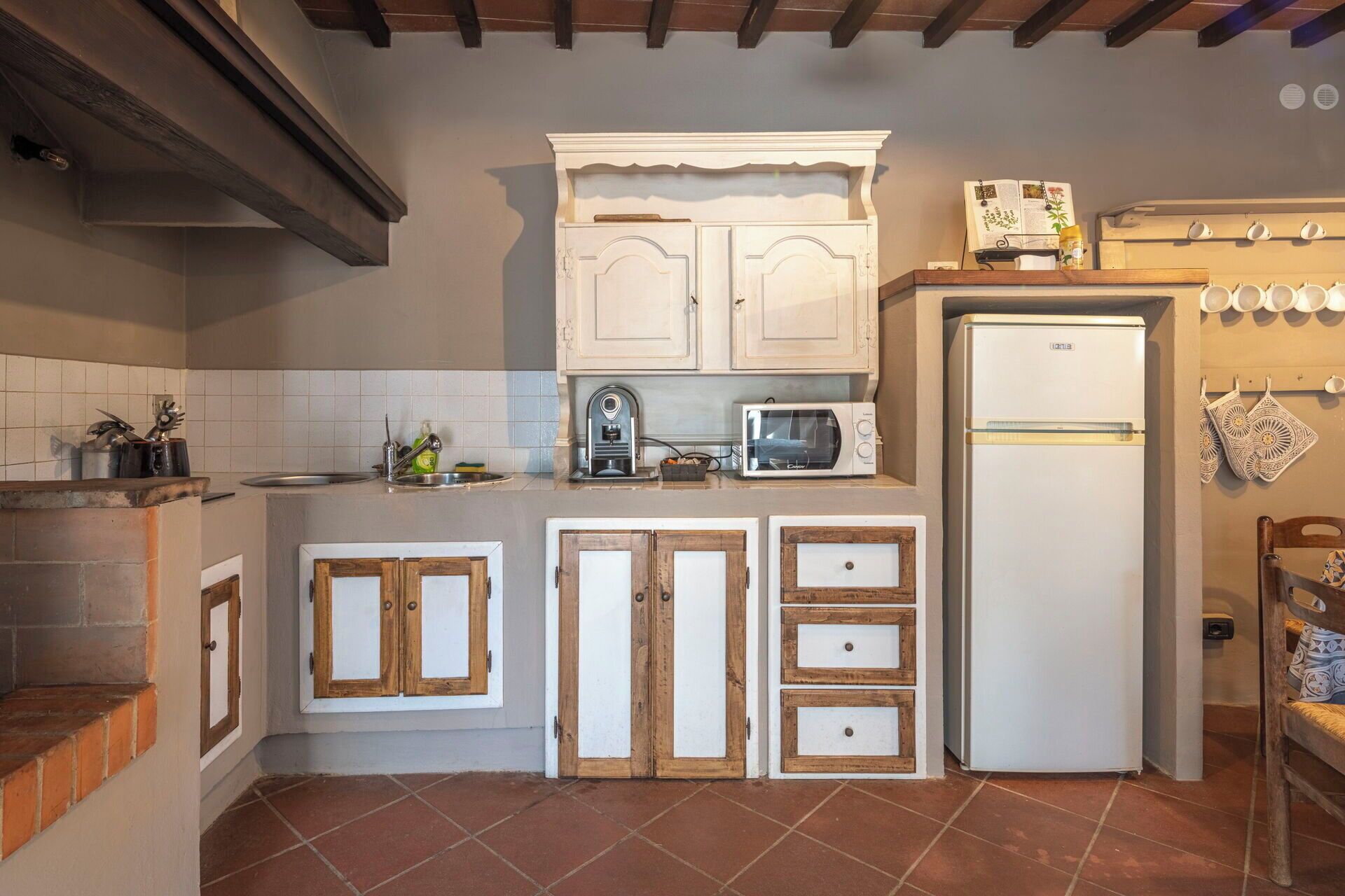 A compact kitchen with white cabinets, a microwave, a refrigerator, and a tiled backsplash.