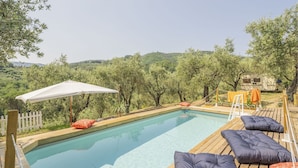 Ein Pool mit Holzterrasse und weißem Sonnenschirm.