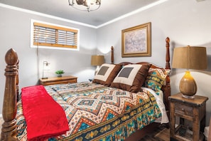 A bedroom with a bed, bedside tables, a lamp, a window with blinds, and a framed picture on the wall. - Salt Block - The Rustic 1 | Cozy 2BR in Bandera (Bandera)
