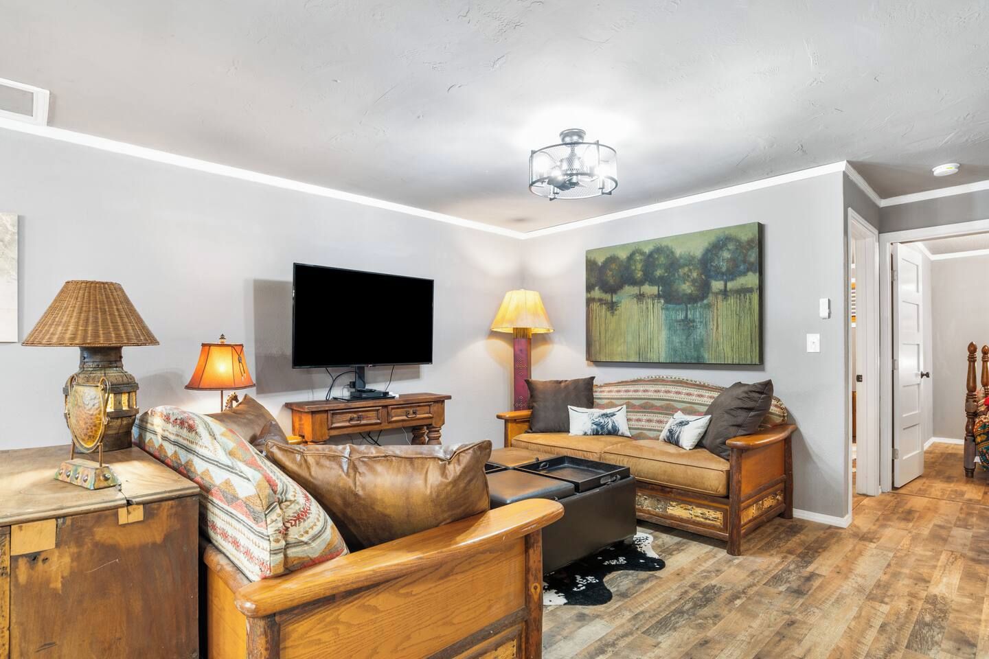 A living room with a television, sofa, and lamps.