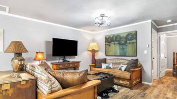 A living room with a television, sofa, and lamps.