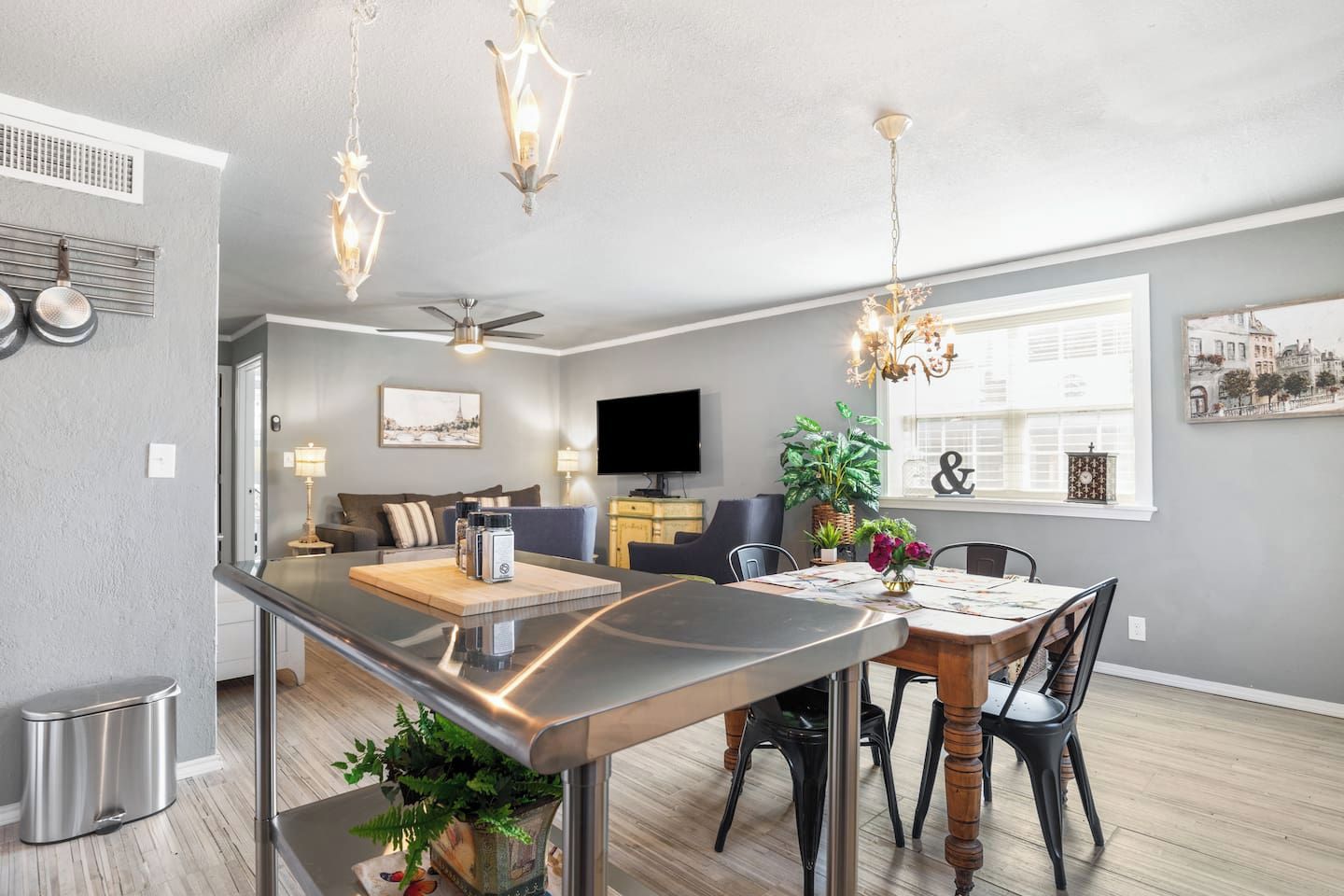 A modern kitchen with a central island, dining area with chairs, a sofa, and a TV in the living room.