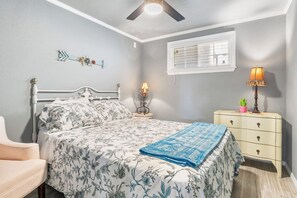Ein Schlafzimmer mit Bett, Nachttisch, Lampe, Schminktisch und einem dekorativen Pfeil an der Wand.