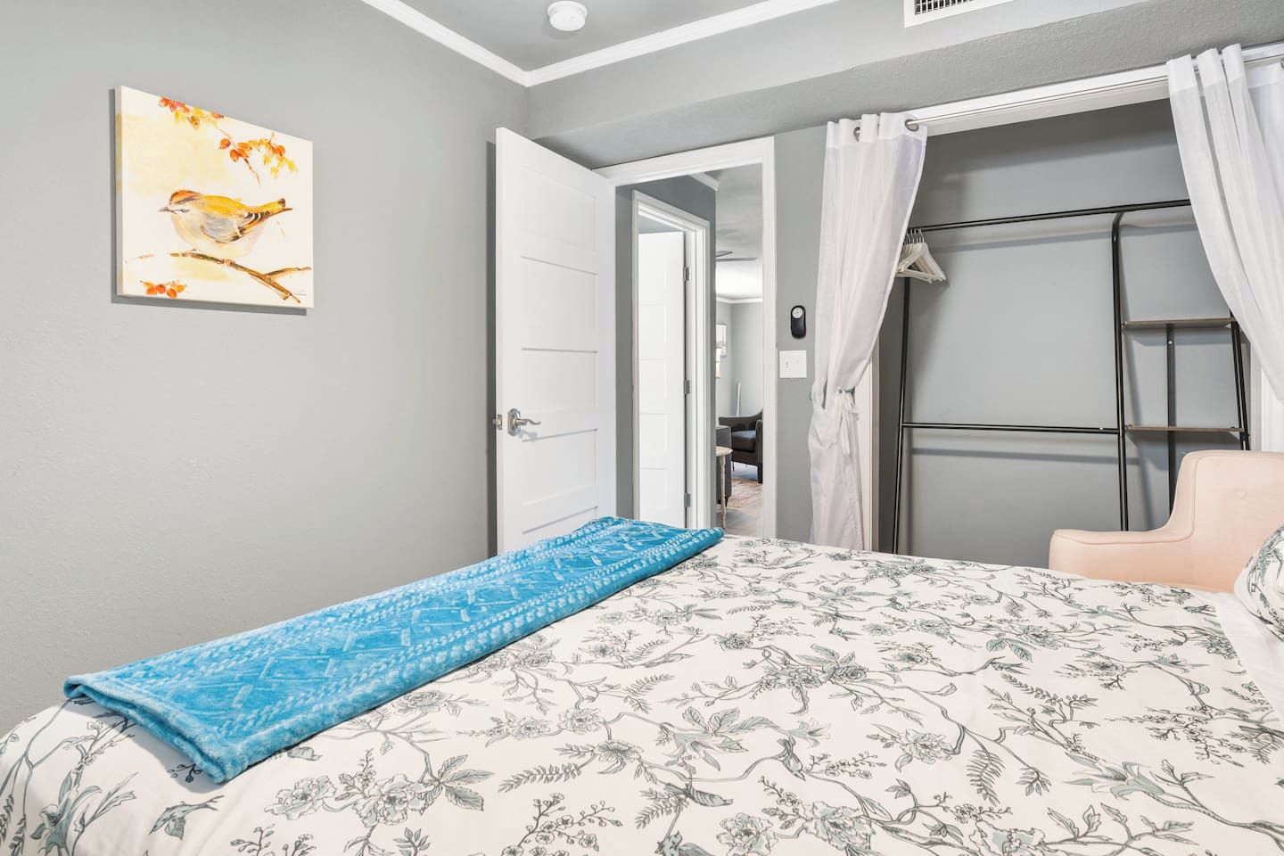 A bedroom with a bed, a chair, a door, and a painting on the wall.