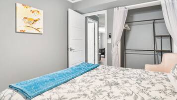 A bedroom with a bed, a chair, a door, and a painting on the wall.