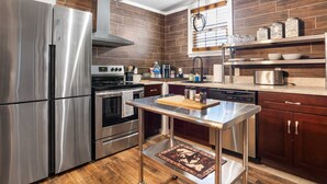 Una cucina moderna con elettrodomestici in acciaio inossidabile, una schiena di piano in legno e un'isola centrale con tagliere.