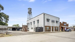 Un edificio a due piani con una torre d'acqua, un garage e un negozio con un'auto parcheggiata davanti.