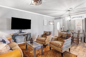 A living room with a flat-screen TV, two armchairs with patterned upholstery, a coffee table, and a patterned rug. - Salt Block - The Cowboy 4 | Suite Near 11th St Bar (Bandera)