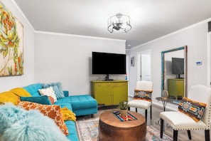 A living room with a sofa, armchair, coffee table, and a television. - Salt Block-Santa Fe 5 | Walk to 11th St| 2BR Suite (Bandera)