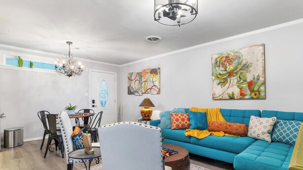 A living room with a blue sofa, a dining table with chairs, a chandelier, and artwork on the walls. - Salt Block-Santa Fe 5 | Walk to 11th St| 2BR Suite (Bandera)