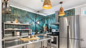 A modern kitchen with stainless steel appliances, a central island, and teal backsplash tiles. - Salt Block-Santa Fe 5 | Walk to 11th St| 2BR Suite (Bandera)