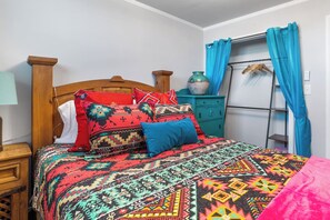 A bed with a patterned bedspread, a wooden headboard, and a nightstand with a lamp. - Salt Block-Santa Fe 5 | Walk to 11th St| 2BR Suite (Bandera)