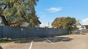 A parking lot with numbered parking spaces and a fence with numbers. - Salt Block-Santa Fe 5 | Walk to 11th St| 2BR Suite (Bandera)