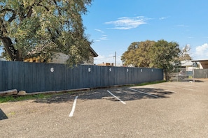 A parking lot with numbered parking spaces and a fence with numbers. - Salt Block-Santa Fe 5 | Walk to 11th St| 2BR Suite (Bandera)