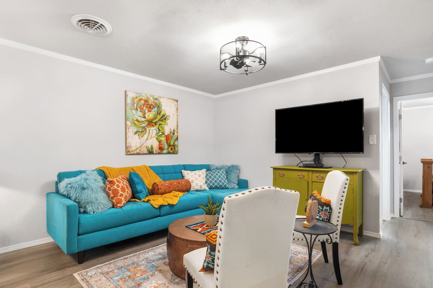 A living room with a blue sofa, a television, a green cabinet, and a patterned rug.