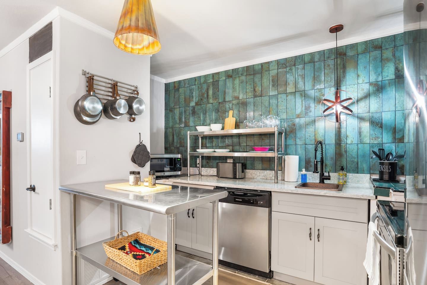 A modern kitchen with a dishwasher, microwave, and a variety of utensils on the counter.