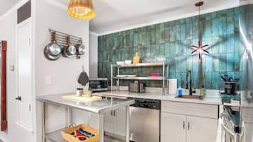 A modern kitchen with a dishwasher, microwave, and a variety of utensils on the counter.