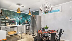 A modern kitchen with stainless steel appliances, a dining area with a patterned tablecloth, and a chandelier. - Salt Block-Santa Fe 5 | Walk to 11th St| 2BR Suite (Bandera)