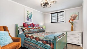 Une chambre à coucher avec un lit, une chaise, une commode et des œuvres d’art accrochées aux murs.