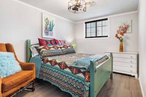 A bedroom with a bed, a chair, a dresser, and artwork on the walls. - Salt Block-Santa Fe 5 | Walk to 11th St| 2BR Suite (Bandera)