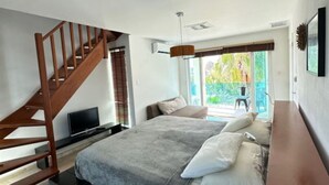 Een moderne slaapkamer met een bed, een houten trap, een televisie en uitzicht op groen.