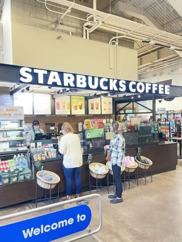 Un kiosque Starbucks avec une pancarte « Bienvenue », un caissier et des clients au comptoir.